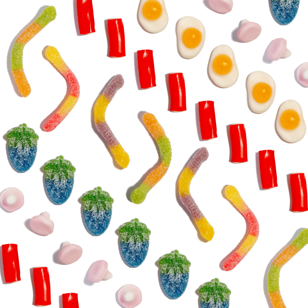 Assorted colourful gummy sweets and sour treats on a white background.